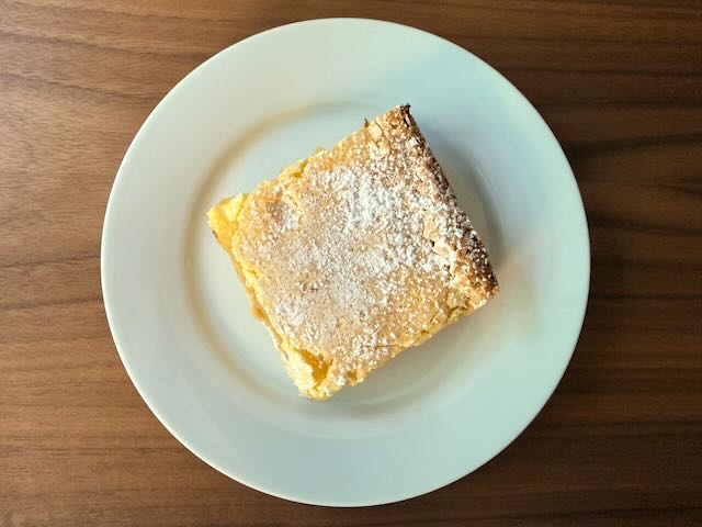 Lemon bar dusted with powdered sugar on a white plate